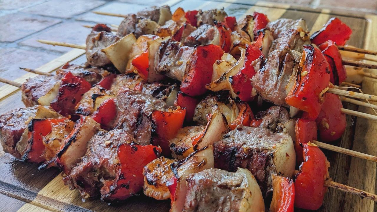 Grilled skewers with cubes of pork tenderloin and large shrimp alternating with chunks of bell peppers and onions. The skewers have a shiny glaze with a reddish hue.