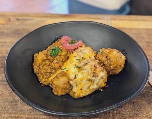 A bowl of the Cozy Gnocchi Meatball Bake, featuring golden cauliflower gnocchi, turkey meatballs, and lentil soup gravy, topped with a bubbly 3 cheese blend and fresh parsley.