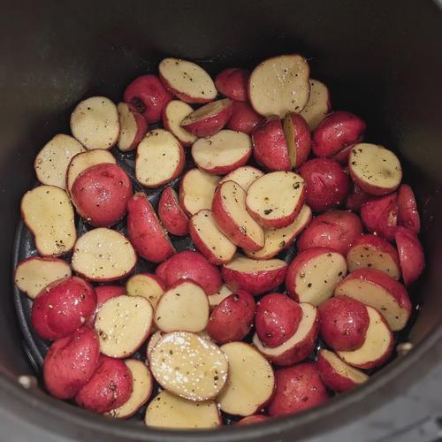 Uncooked baby potatoes in an air fryer basket.