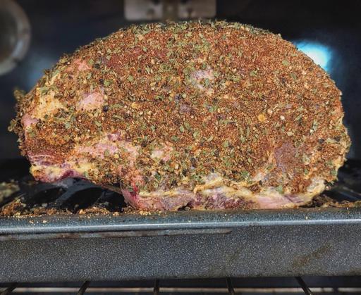 Fully seasoned, raw rib roast on a pan in the oven before cooking.