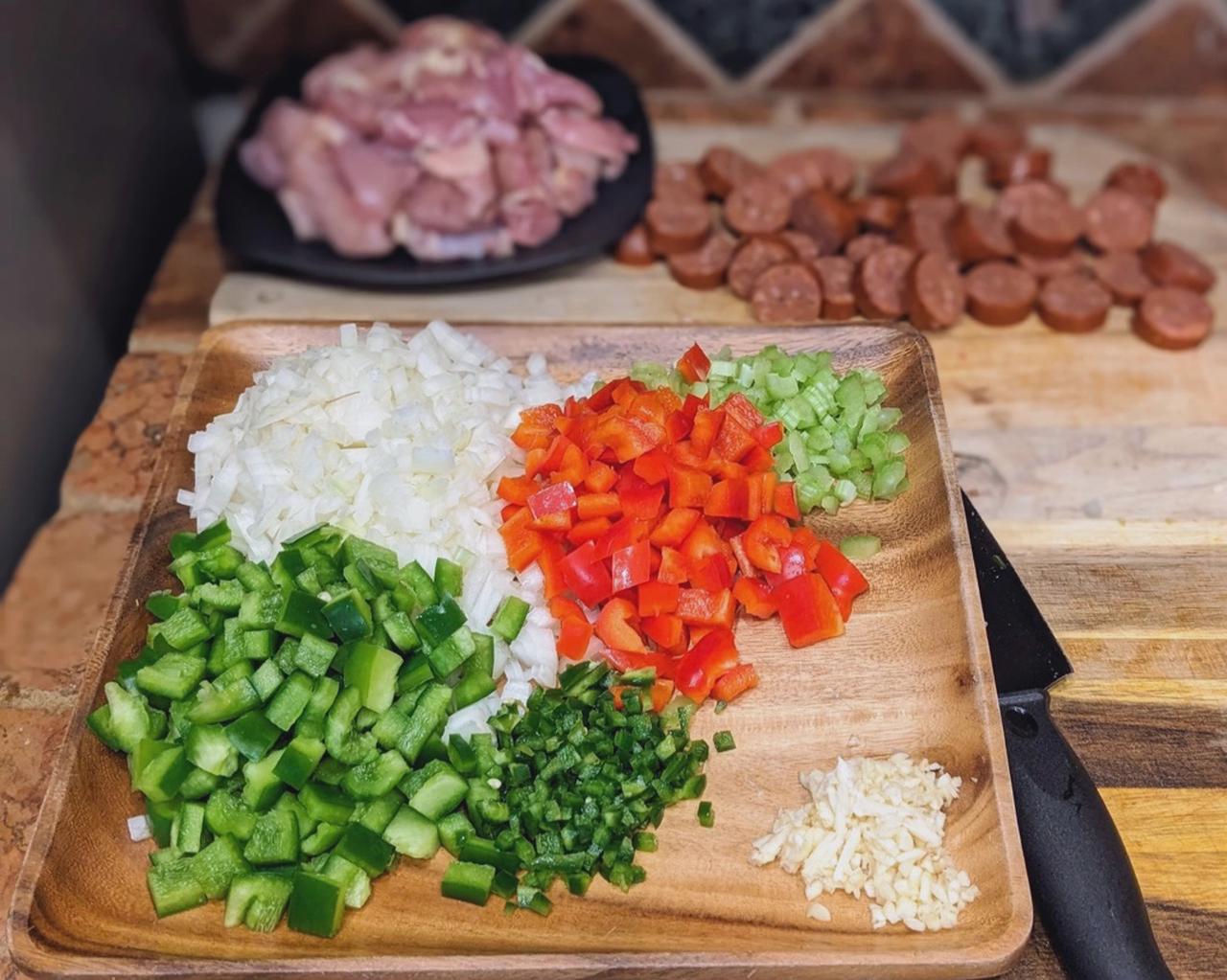 Diced vegetables, chicken, and sausage on a cutting board, ready to be used in the Jambalaya recipe.