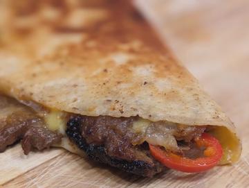 Close-up of the assembled quesadilla, showcasing the golden-brown, crispy tortilla and the flavorful, colorful filling.