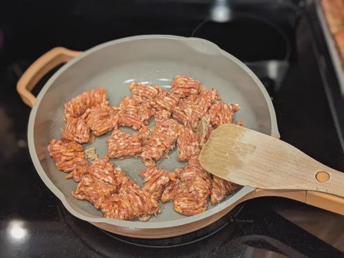 Spicy Italian sausage browning in a skillet.