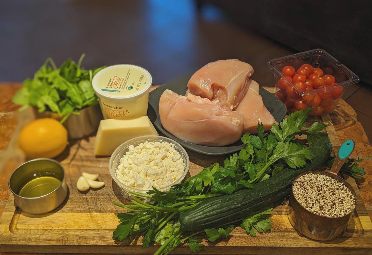 Platter of Spinach & Ricotta Stuffed Chicken With Quinoa Salad ingredients on a cutting board.