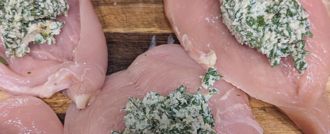 Raw chicken breasts stuffed with ricotta and spinach, ready to be baked.