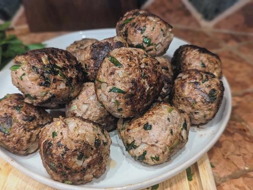 Seared meatballs on a white plate.