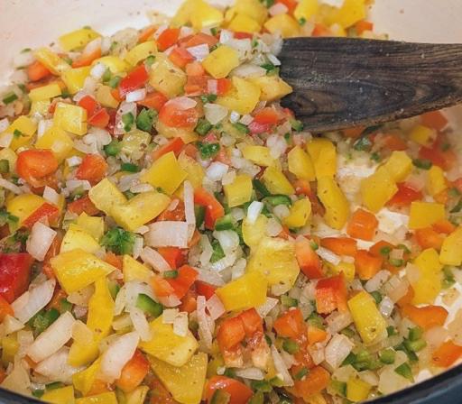 Diced onion, bell peppers, and jalepeños sauteing in a dutch oven.