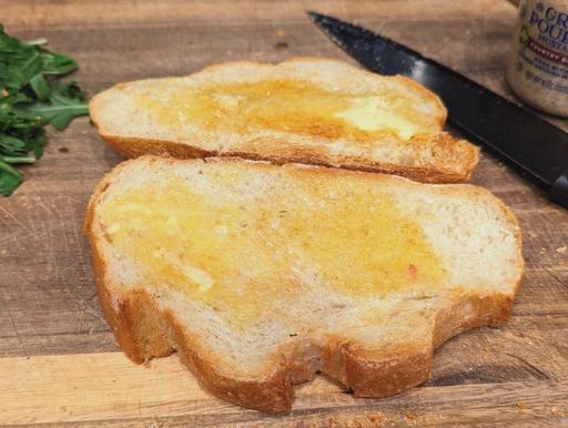 Two slices of sourdough bread, toasted and buttered.