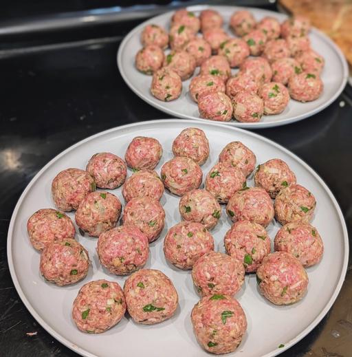 1 inch, raw meatballs on white plates.